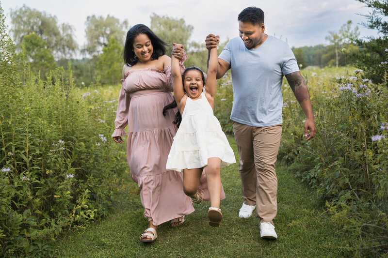 Joyful girl being swung by her parents