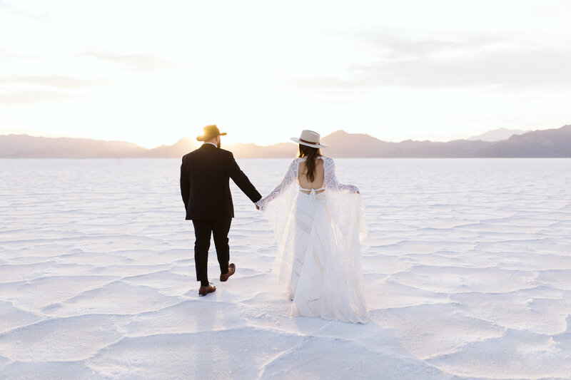 Bride and groom walking hand-in-hand across the expansive salt flats, photographed by an Oregon Coast Elopement and Wedding Photographer.