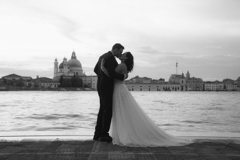 Elopement Photo Ideas | Eloping couple embrace passionately with the Venice skyline behind them