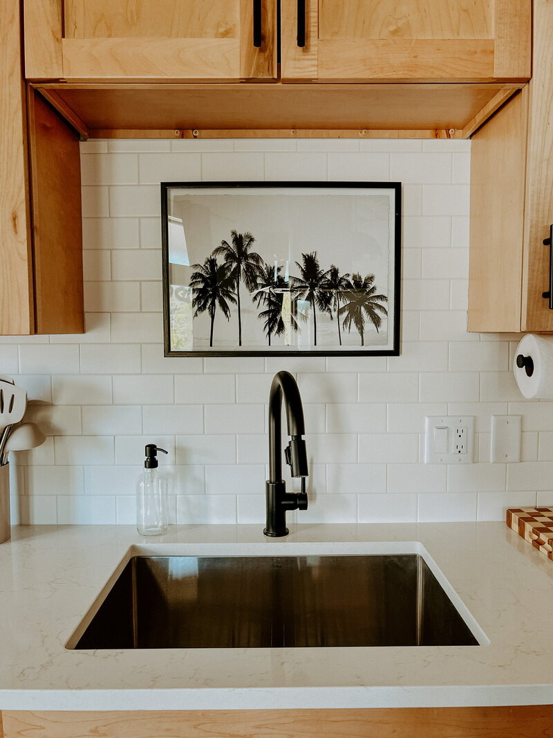 kitchen with white subway tile, wood cabinets and black hardware