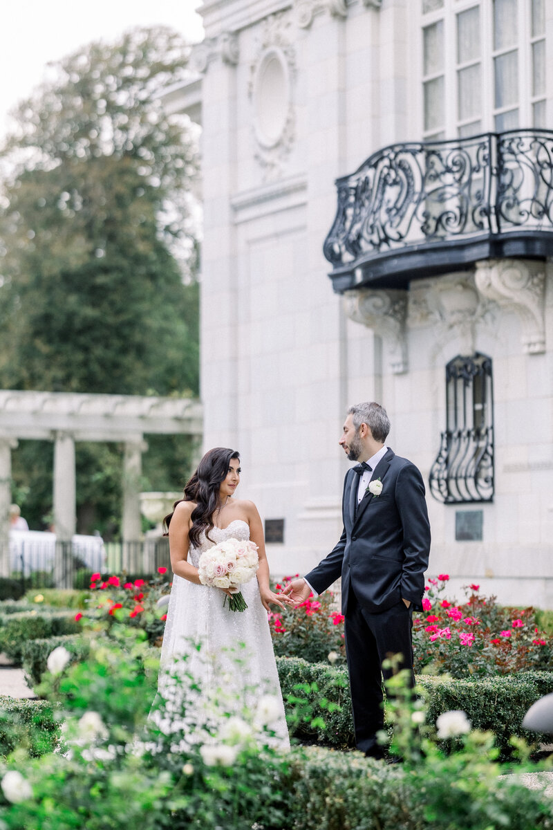 Bride and groom stroll through garden in Newport at Rosecliff mansion