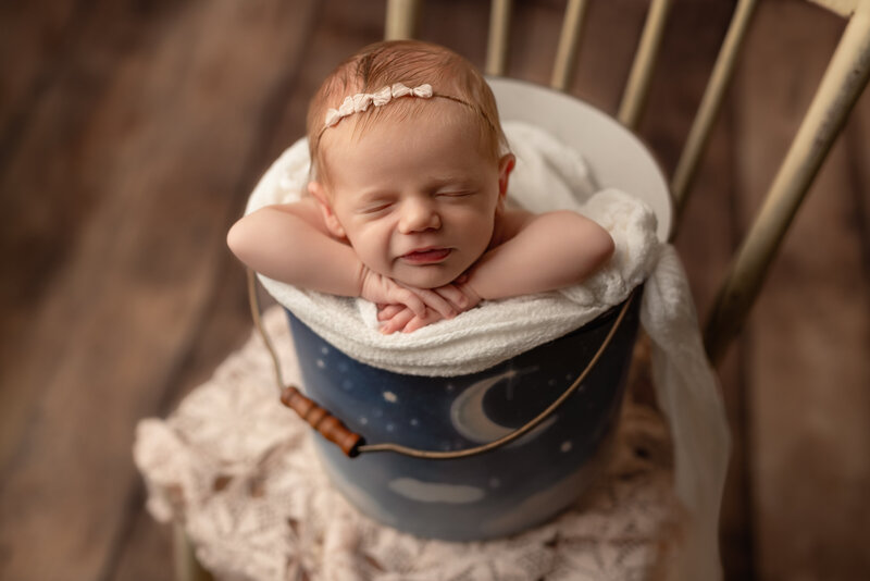 A celestial bucket photo featuring a newborn girl in dreamy moonlight tones and soft handcrafted details.