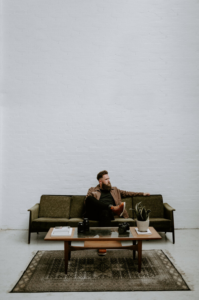 Creative wedding wedding photographer Mark Horton sitting on a sofa in a Scandinavian style photography studio.