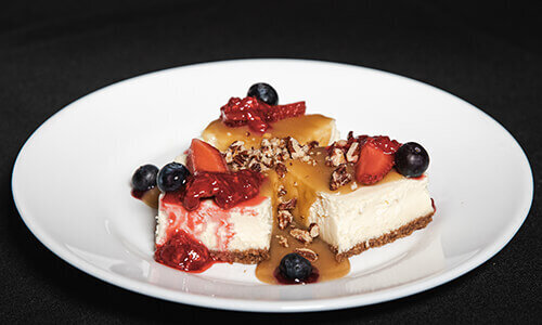 Chuckanut Bay New York cheesecake bites with whiskey caramel sauce, fresh berries, toasted pecans, and port berry sauce