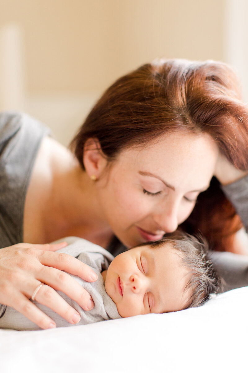 A mom sweetly smelling her newborns hair during an in-home newborn session in Lexington KY.