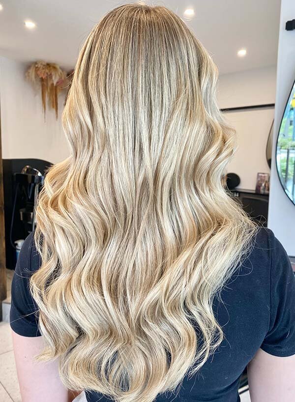 Long blonde hair styled in loose, glossy waves, showcasing expert coloring at Blake & Kwan Hair Salon in Sydney.