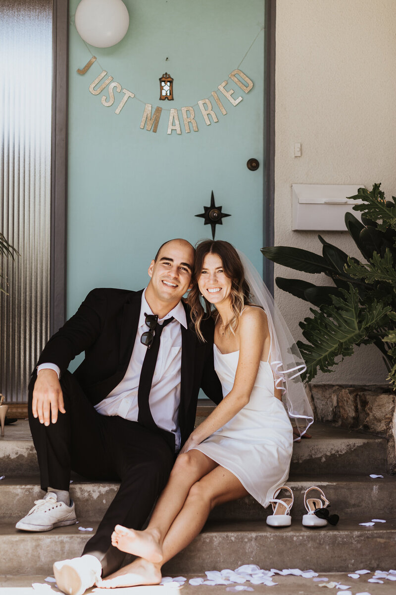 Wedding Photographer, bride in her dress and groom in his tux walk hand-in-hand down the beach