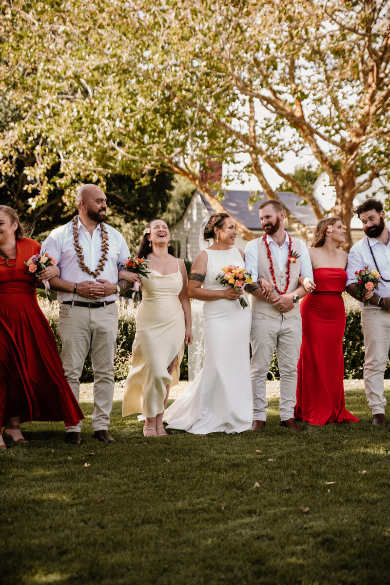 Colourful sunset themed bridal party walking together during their photoshoot at abbeville estate in auckland