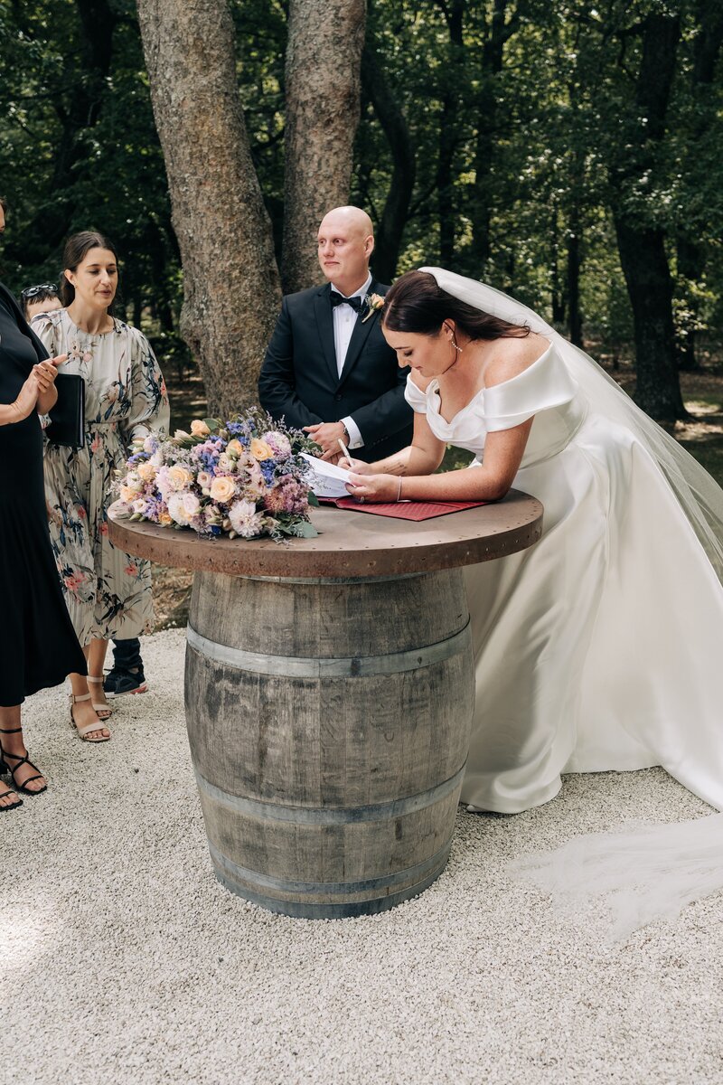 a wedding couple sign marriage certificate on wine barrel at bangor farm deer shed in darfield