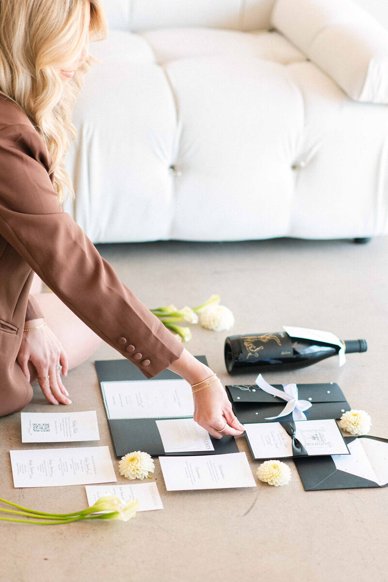 wedding stationer placing custom invitations into a flat lay for detail photos