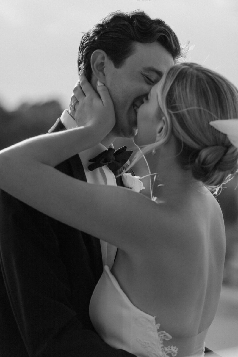 A newlywed couple smiling into a kiss 