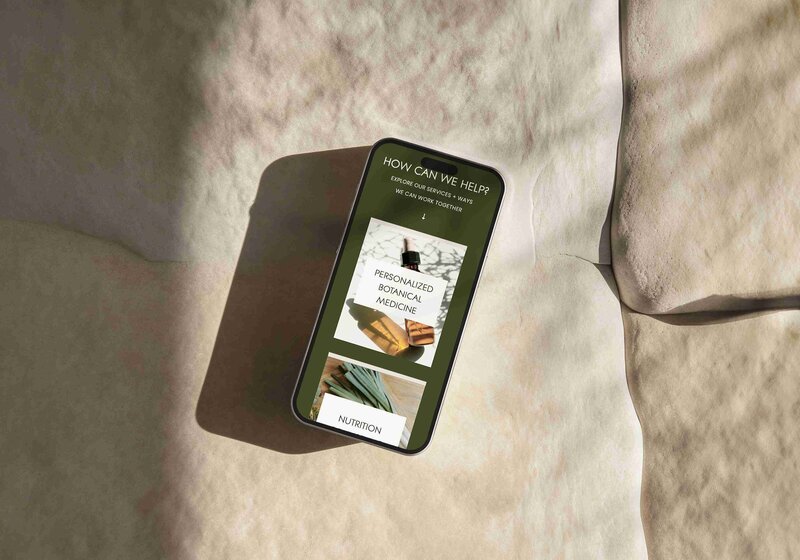 A smartphone resting on a textured stone surface, featuring a holistic website design by Unica Formo.