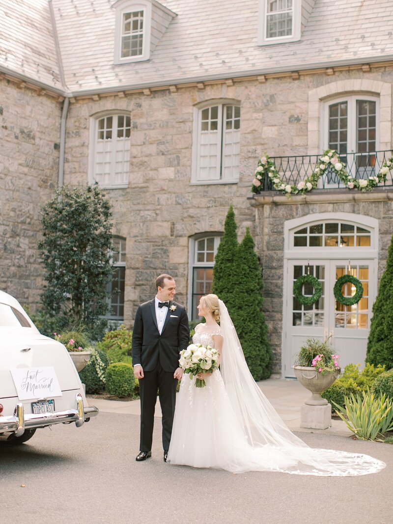 Bride and groom pose outside beautiful New England venue with stone facade