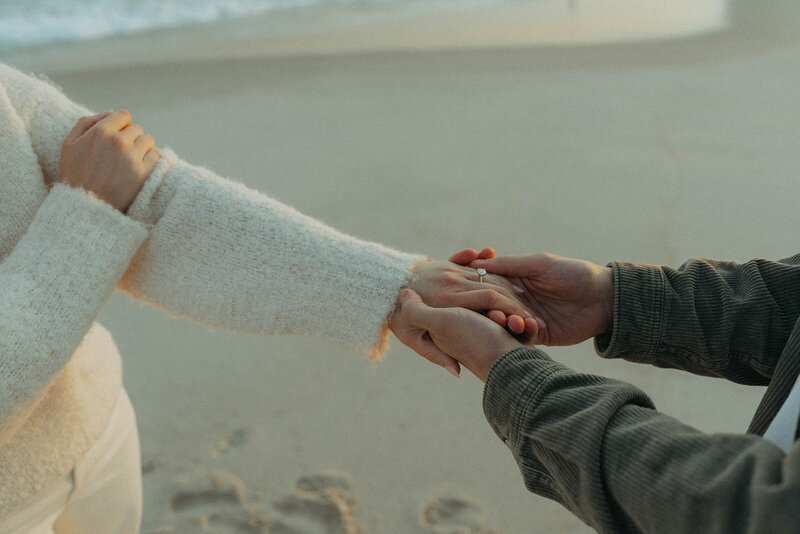 couple holding hands during beach engagement photos, captured by Elsie Goodman, an NYC engagement and couples photographer