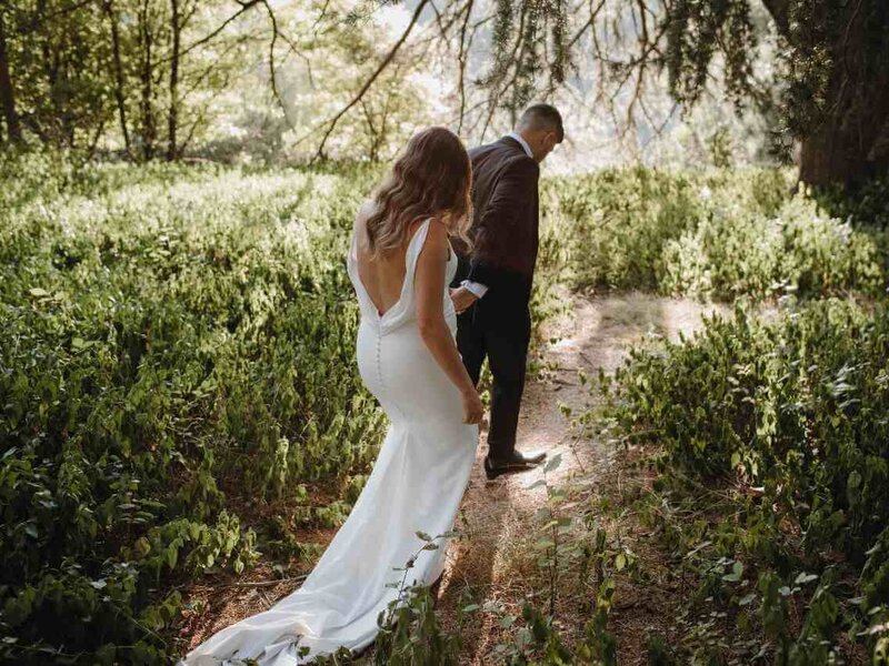Bride and groom walking in forrest holding hands