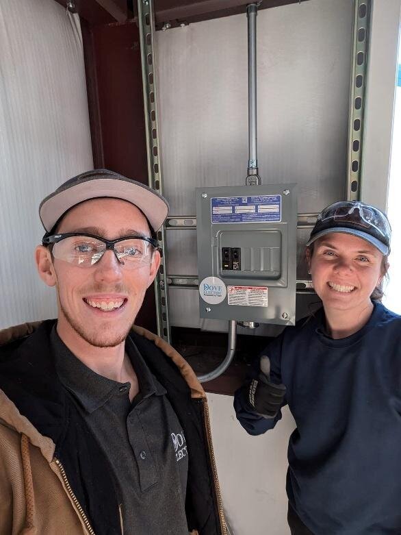 Two electricians in Albuquerque smiling next to garage wiring