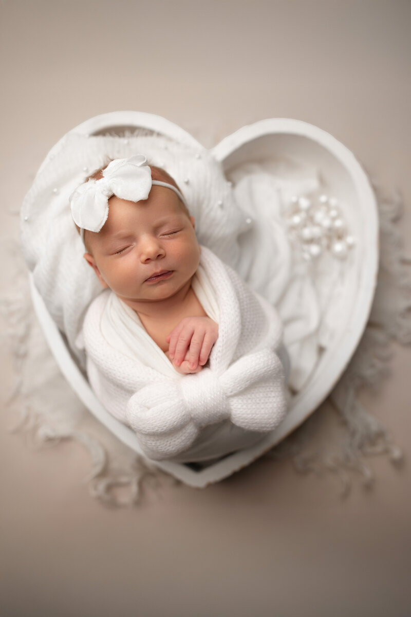Newborn baby girl wrapped in whte blanket during studio session in Connecticut