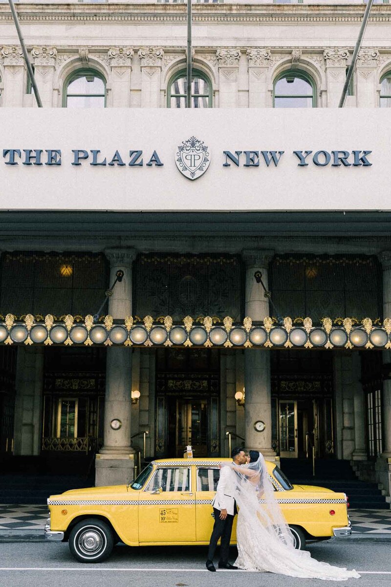 bride and groom at yellow taxi at Plaza Hotel