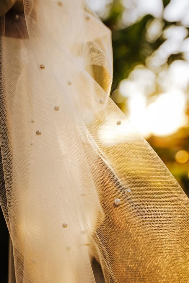 detail of pearls on a custom bridal veil during golden hour