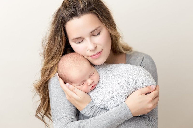 Newborn boy pose with mom in grey