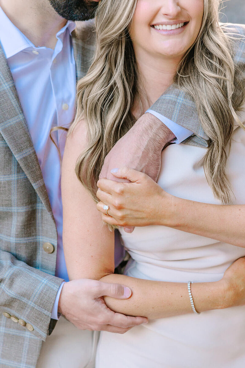 Close-up of man embracing woman from behind, with her engagement ring visible, during a romantic Paris photoshoot near the Eiffel Tower and in Montmartre.