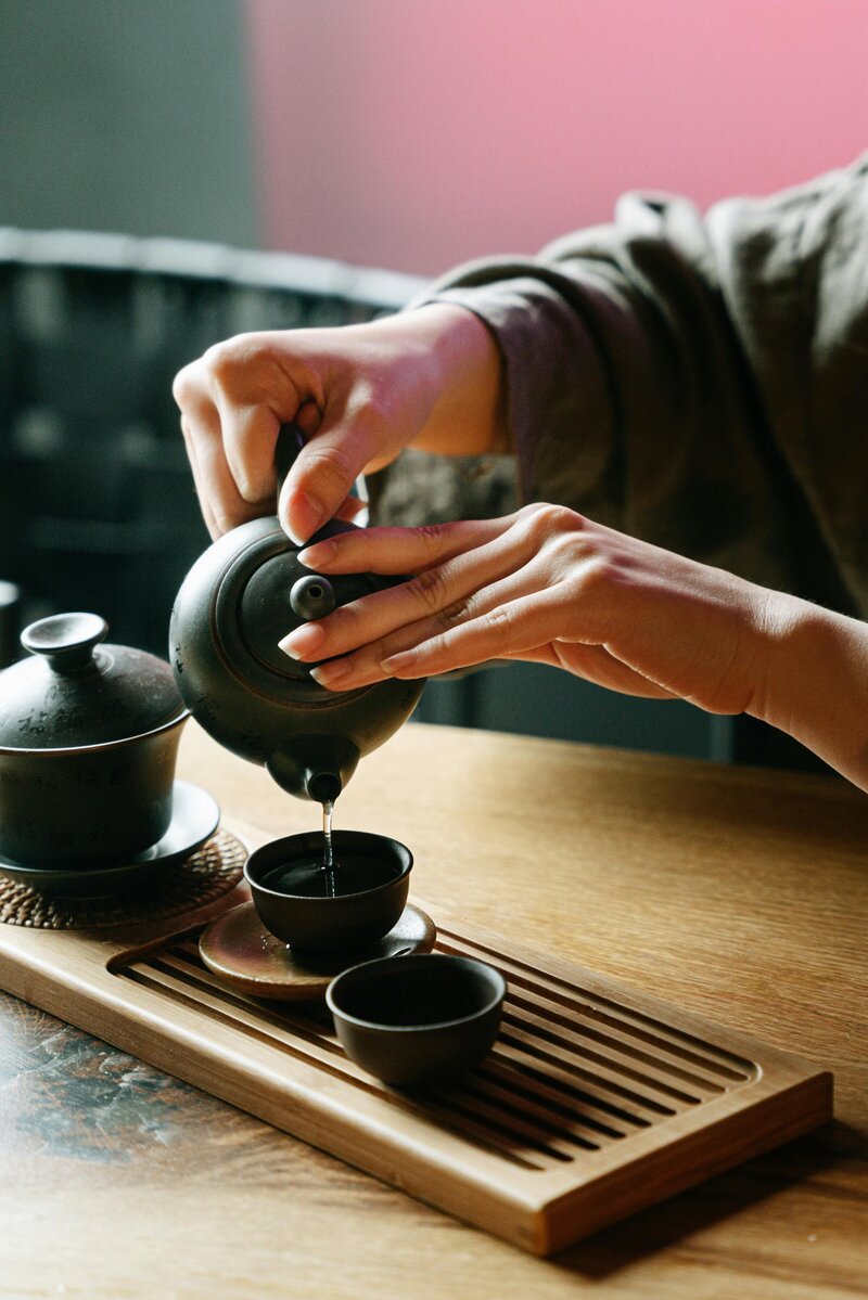 Hands pouring tea from a traditional Japanese teapot during a cultural tea session