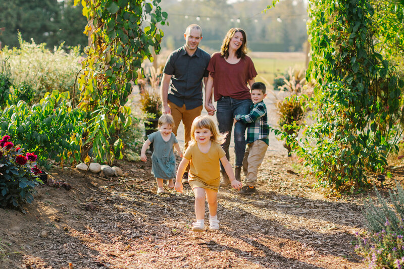 Mom and dad holding hands while three kids run toward the camera