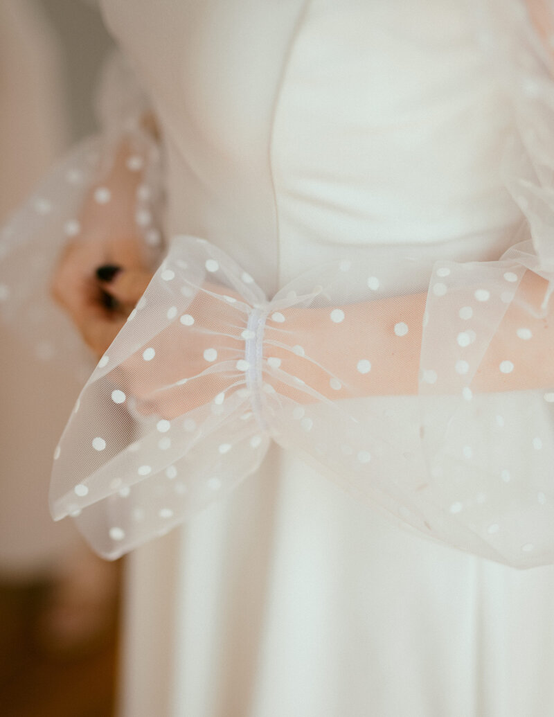 Bride wearing modern white gown with sheer polka dot bow sleeve detail. Styled by Eventive Designs in Austin, Texas.