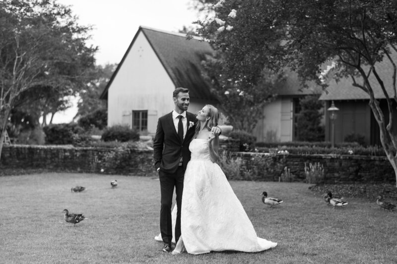 black and white image of bride and groom on lawn surrounded by ducks