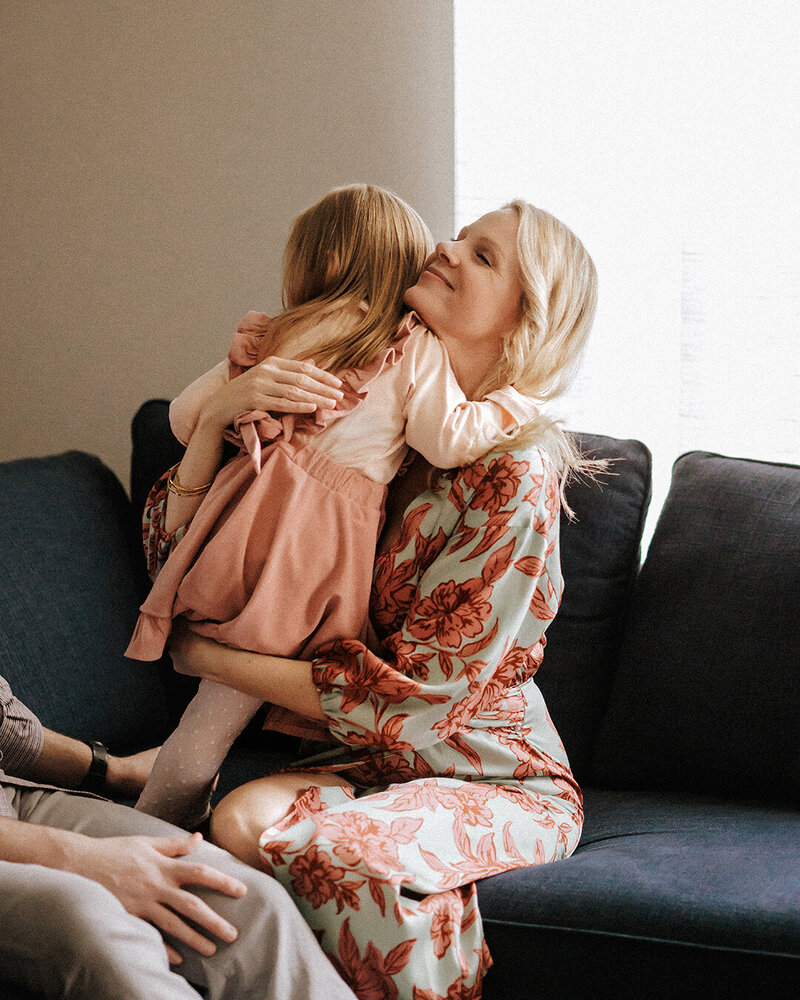 Mother hugging daughter on coach during lifestyle photography session