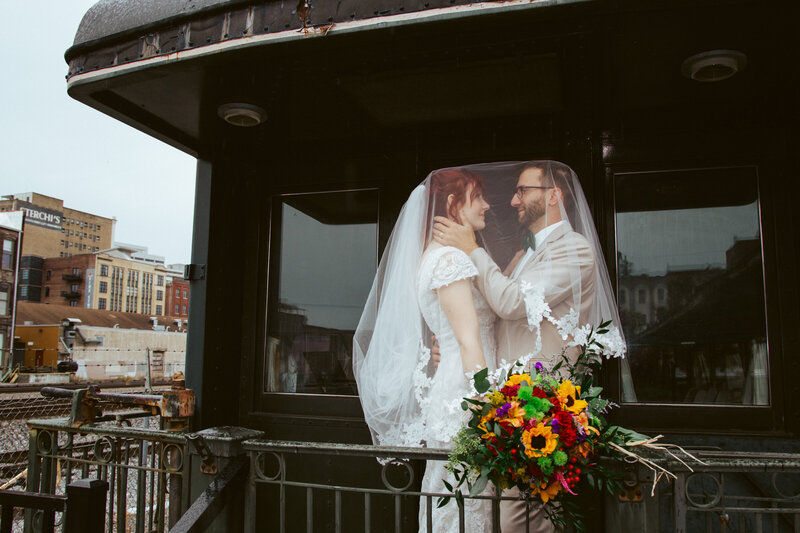 b ride and groom under veil smiling on a train