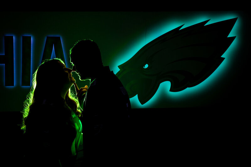 Silhouette of an engaged couple in front of the Eagles logo, showcasing their love for each other and their favorite team.