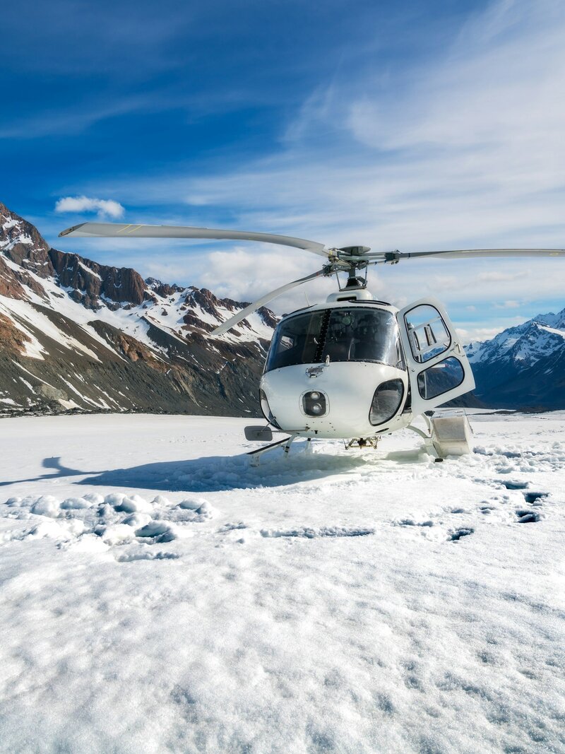 A helicopter landed on a snowy mountain top in Queenstown.