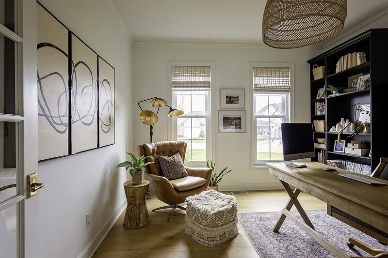 Warm and modern office with a brown chair, wood end table and an arrangement of print with a playful and minimalist pattern