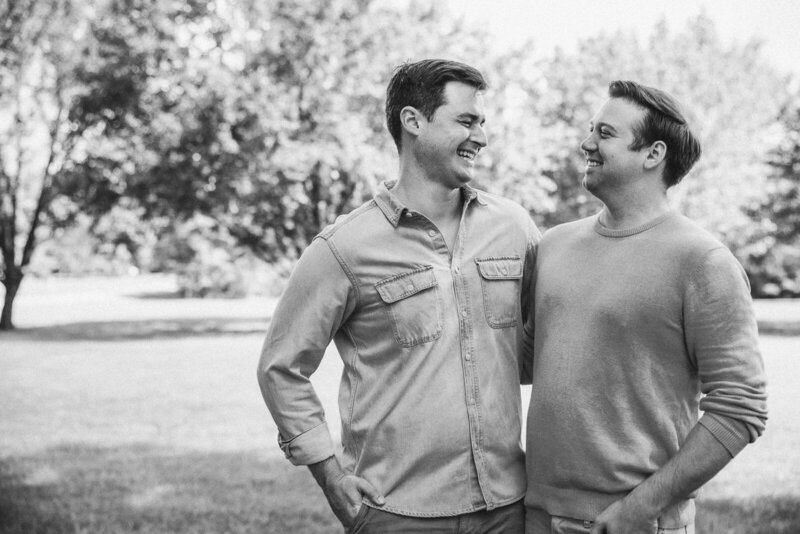 Black and white portrait of a couple looking at each other laughing. 