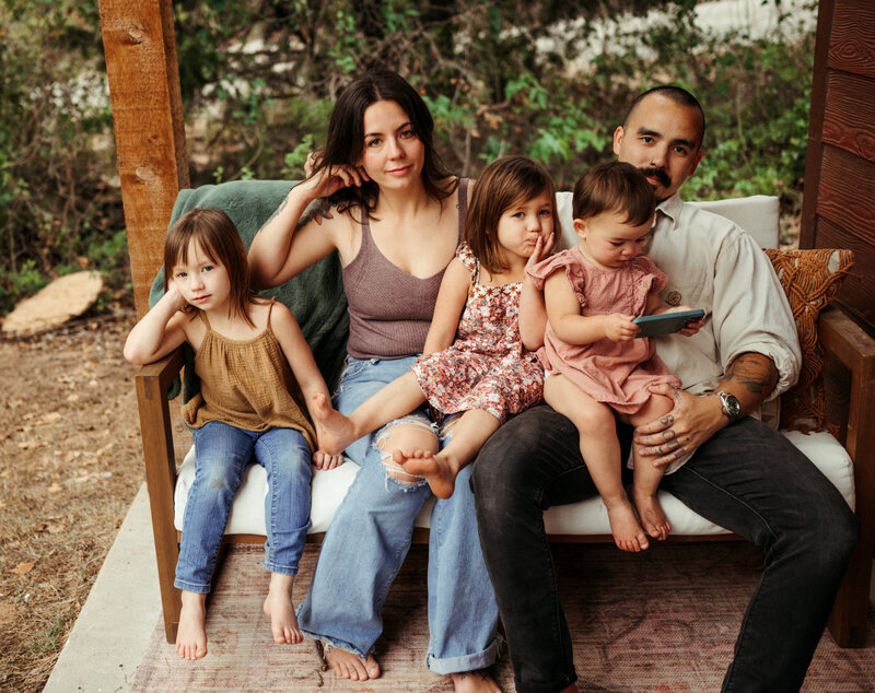 Family of five sitting on a porch swing.