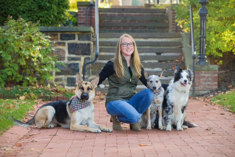 A woman posing with her beloved dogs during a spring or autumn mini session in historic Bethlehem, PA.