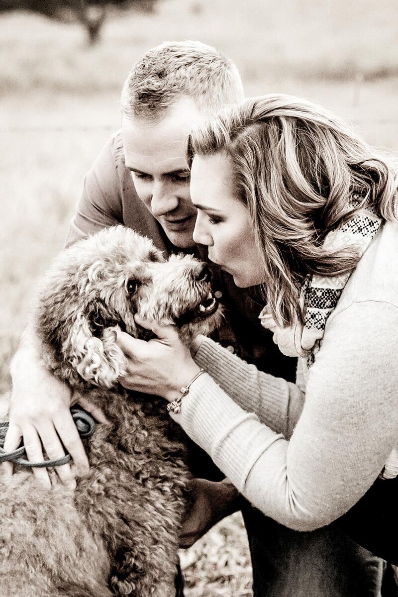 Engagement couple cuddling with their dog