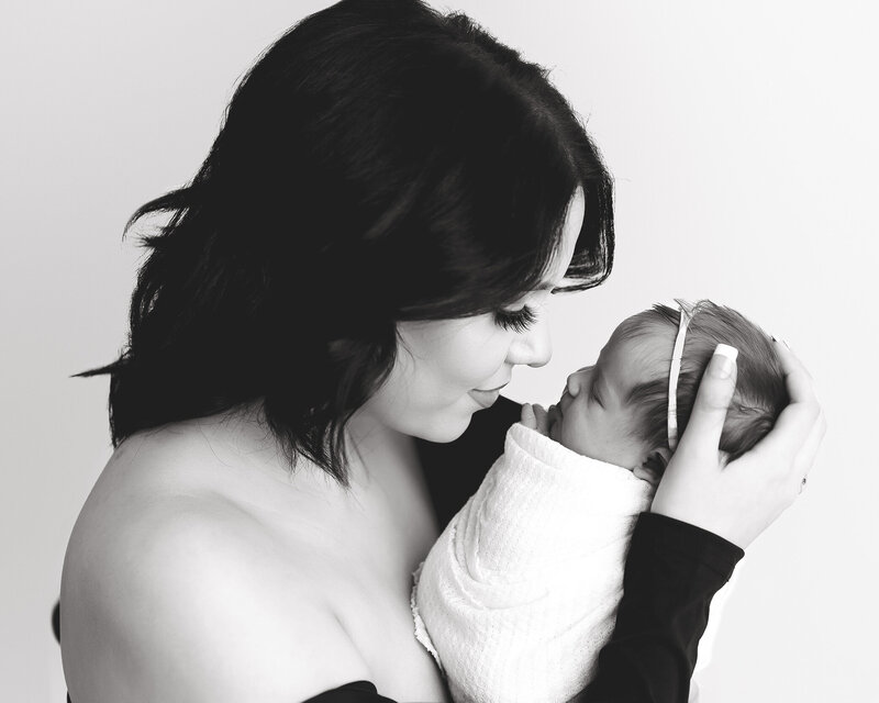 Mom holds daughter nose to nose for black and white picture.