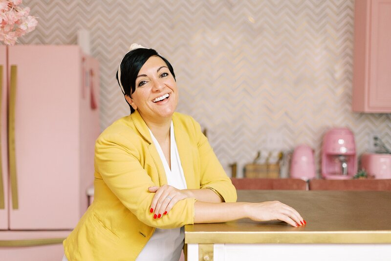 a woman with a pixie haircut is smiling at the camera while standing at the Nashville Pinky House for her branding photos