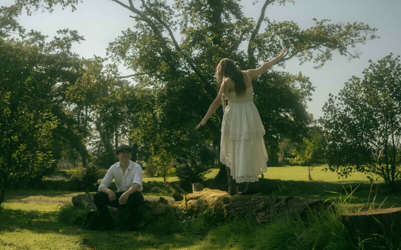 Woman walking on a tree trunk, gazing lovingly at her beloved, captured in a serene and romantic moment amidst nature, celebrating their deep connection