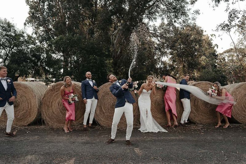 groom spraying champagne while wedding party laugh at Acacia Ridge Wedding