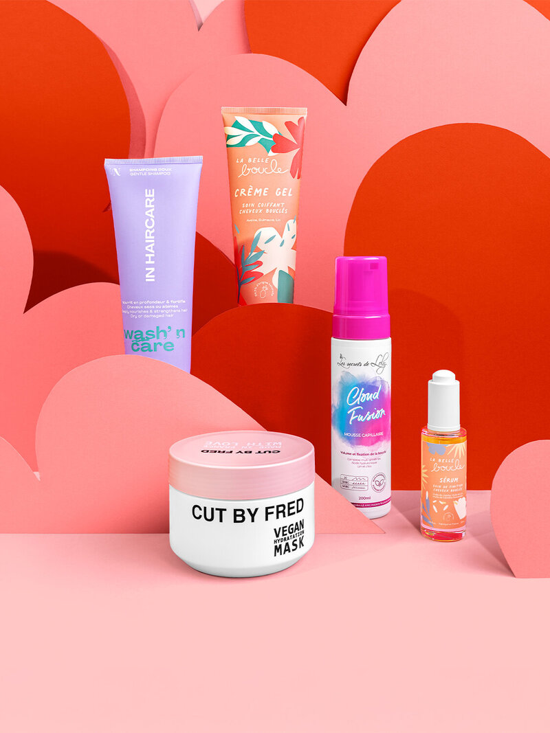 Mise en scène colorée des produits La Belle Boucle sur fond rose et rouge, photographie Studio Helloday.