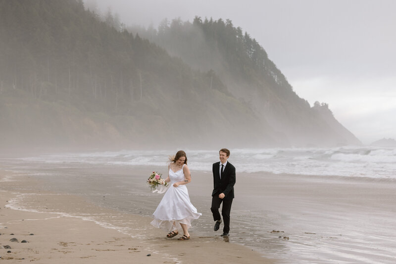 Couple running on a beach on the Oregon Coast.
