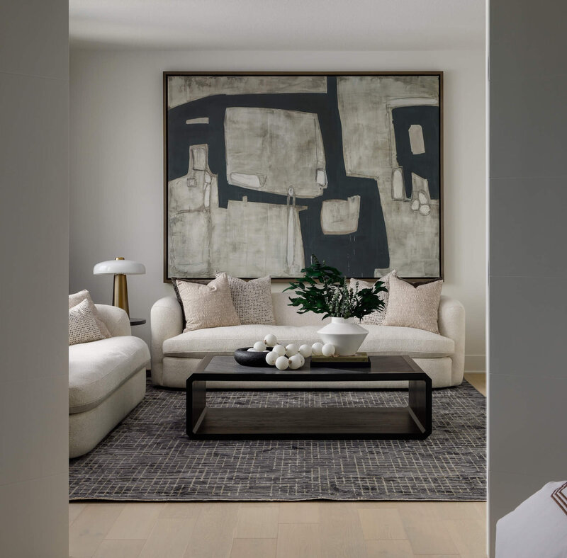 A lounge area with light custom upholstered curved sofas and oversized abstract art. 