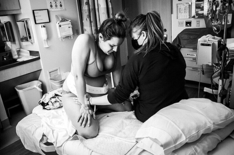 Pregnant woman laboring in hospital bed with doula support