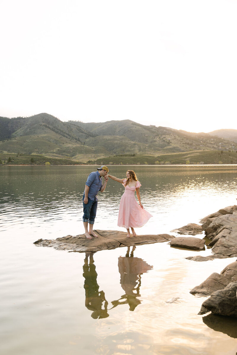 Colorado engagement photos at Horsetooth Reservoir in Fort Collins at sunset with the couple in the water and the groom kissing her hand