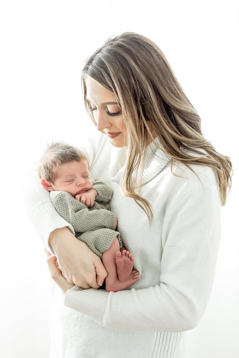 a mom holding a baby against a white backdrop