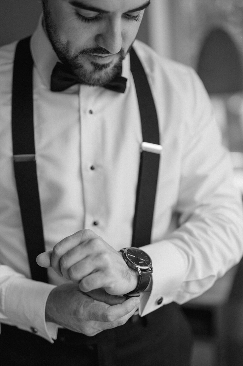 Le marié ajuste sa montre chic lors de ses préparatifs en Montérégie, geste élégant et symbolique capturant l’attention portée aux détails dans un mariage soigné et sophistiqué