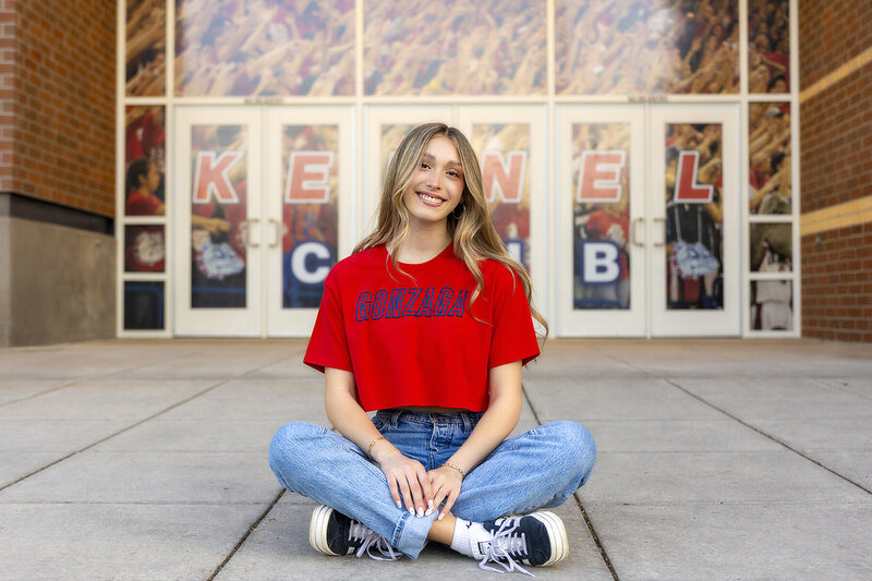 Photo of a blond girl with a Gonzaga flag, jeans and top by a Gonzaga graduation Photographer in Spokane 